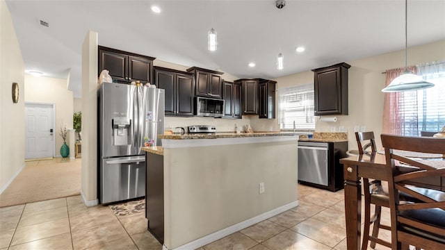 kitchen with light stone countertops, a center island, hanging light fixtures, stainless steel appliances, and light colored carpet