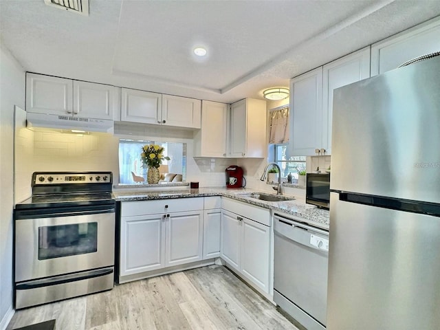 kitchen with white cabinets, backsplash, sink, and stainless steel appliances