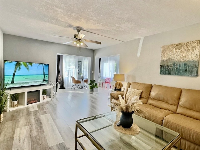 living room featuring ceiling fan, wood-type flooring, and a textured ceiling