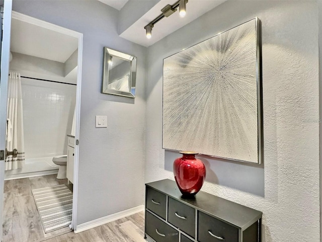 bathroom with toilet, wood-type flooring, and shower / tub combo with curtain