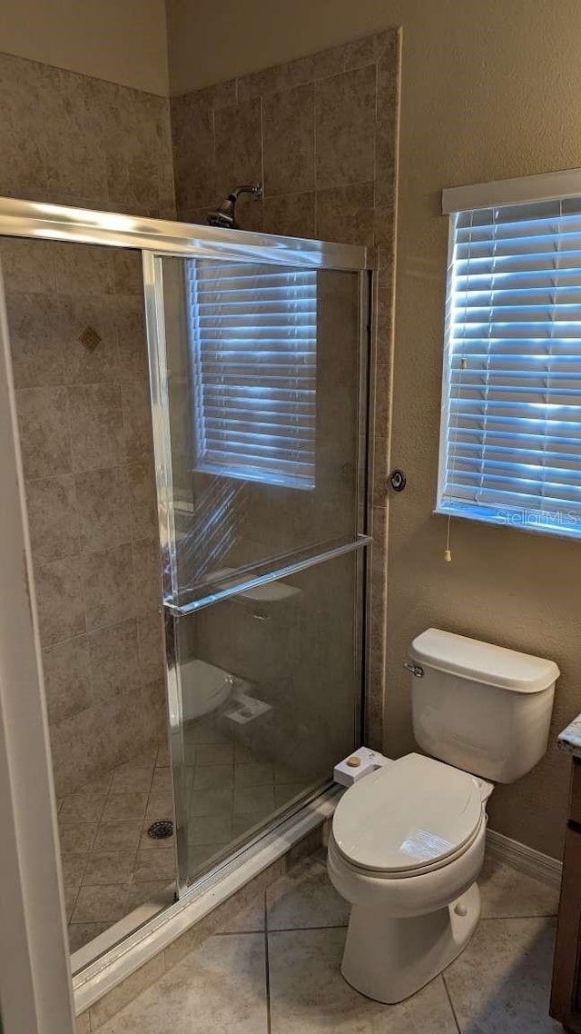 bathroom featuring tile patterned flooring, vanity, toilet, and a shower with shower door