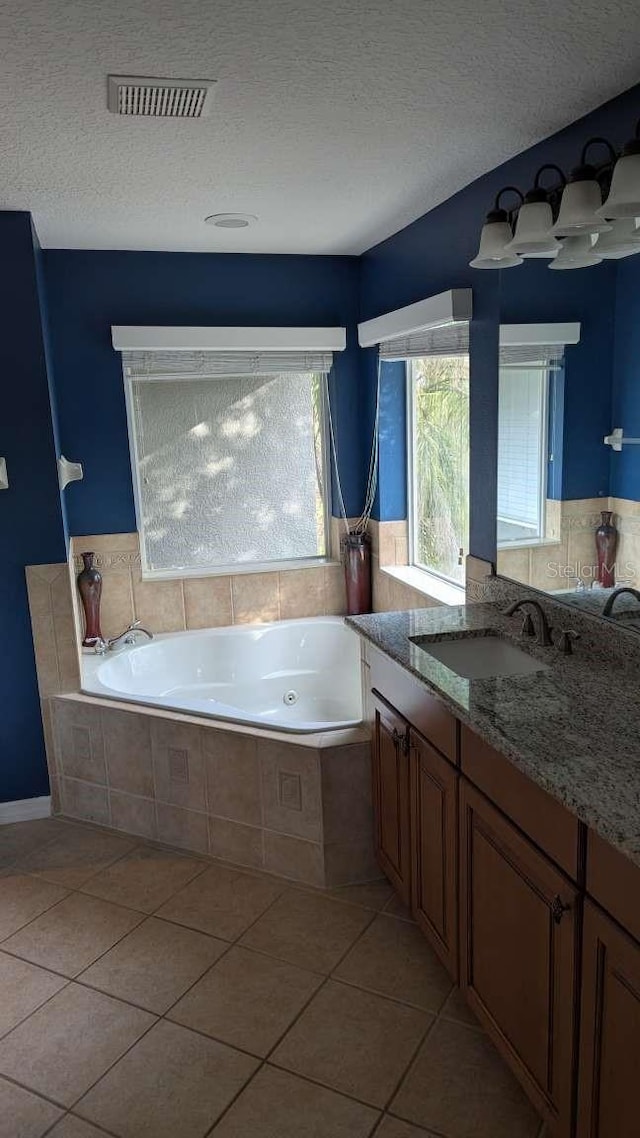 bathroom with vanity, a textured ceiling, a relaxing tiled tub, and tile patterned floors