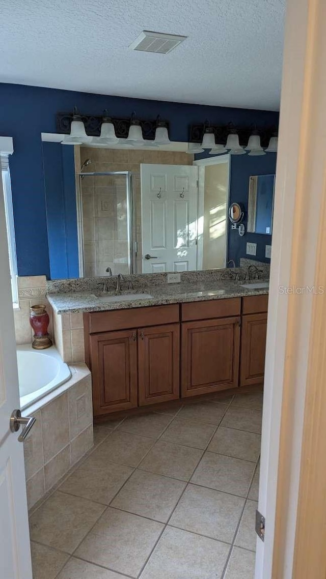 bathroom featuring shower with separate bathtub, vanity, a textured ceiling, and tile patterned floors