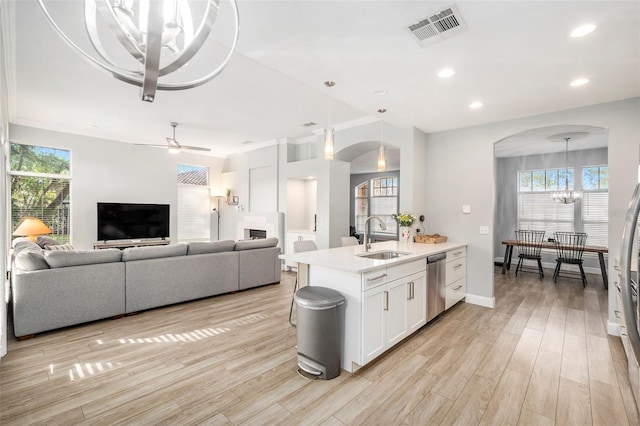 kitchen featuring stainless steel appliances, decorative light fixtures, white cabinets, light hardwood / wood-style flooring, and sink