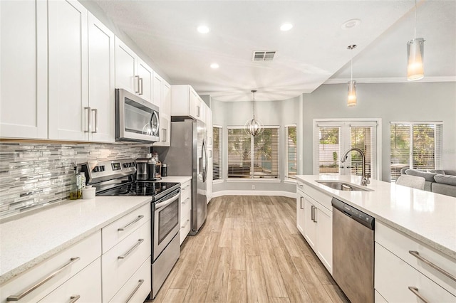 kitchen featuring appliances with stainless steel finishes, white cabinets, decorative light fixtures, and sink