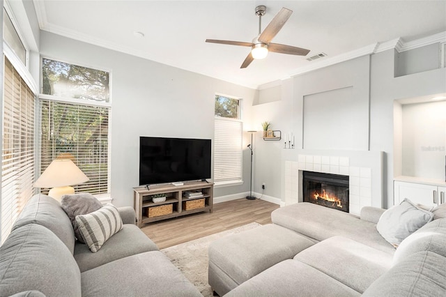 living room featuring crown molding, light hardwood / wood-style floors, and a tile fireplace