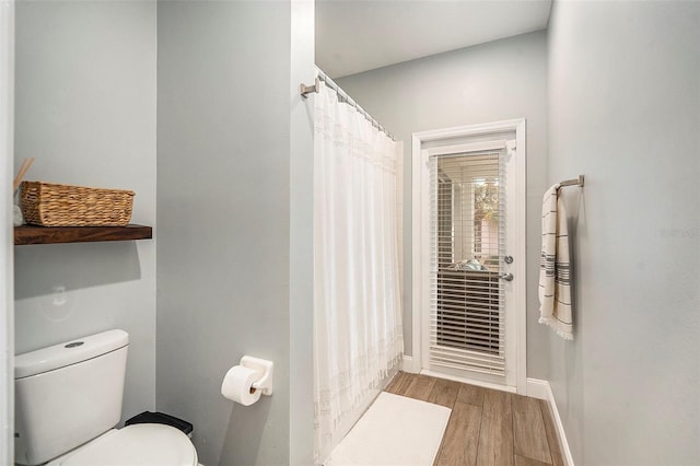 bathroom featuring hardwood / wood-style floors, toilet, and a shower with curtain