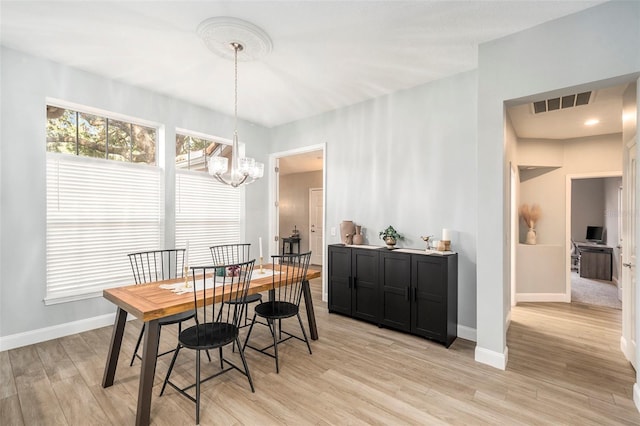 dining space with light hardwood / wood-style floors and a notable chandelier