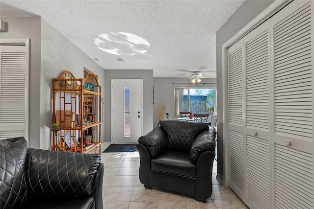 tiled living room with ceiling fan and a textured ceiling