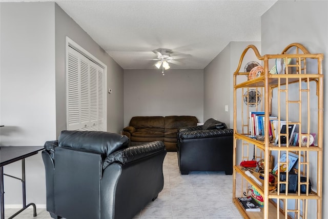 living room featuring ceiling fan and a textured ceiling