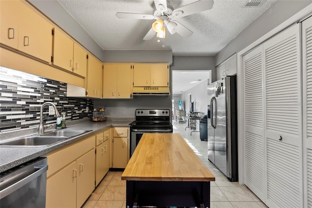 kitchen with wood counters, sink, light tile patterned floors, and appliances with stainless steel finishes