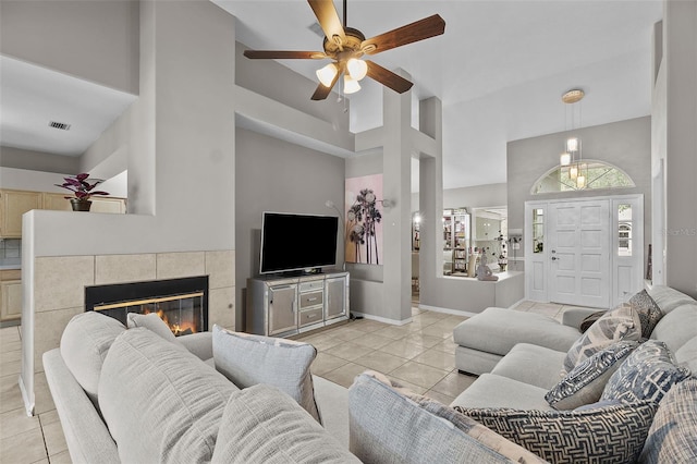 living room with a high ceiling, a tiled fireplace, and light tile patterned floors