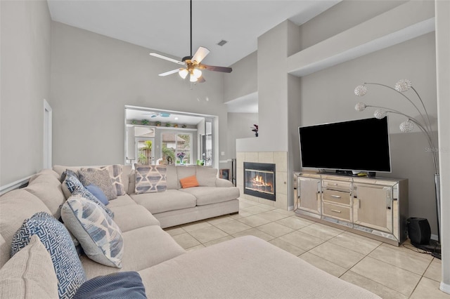 living room with a high ceiling, ceiling fan, a fireplace, and light tile patterned floors