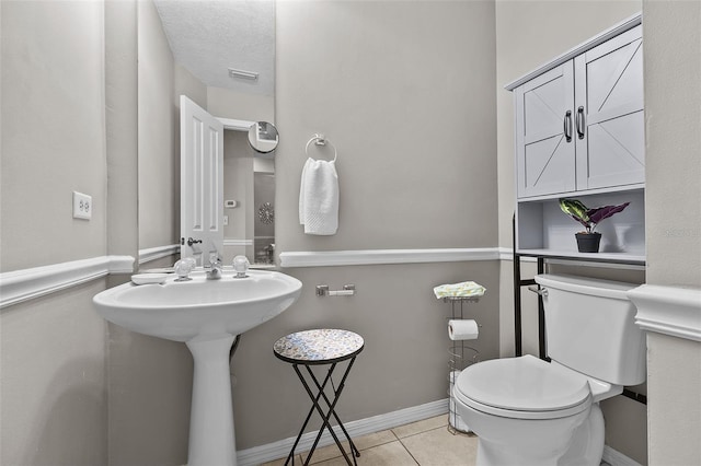 bathroom featuring toilet, a textured ceiling, tile patterned floors, and sink