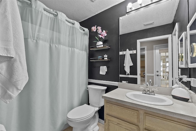 bathroom with a textured ceiling, vanity, and toilet