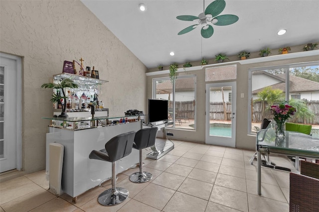 interior space featuring light tile patterned floors, high vaulted ceiling, ceiling fan, and plenty of natural light