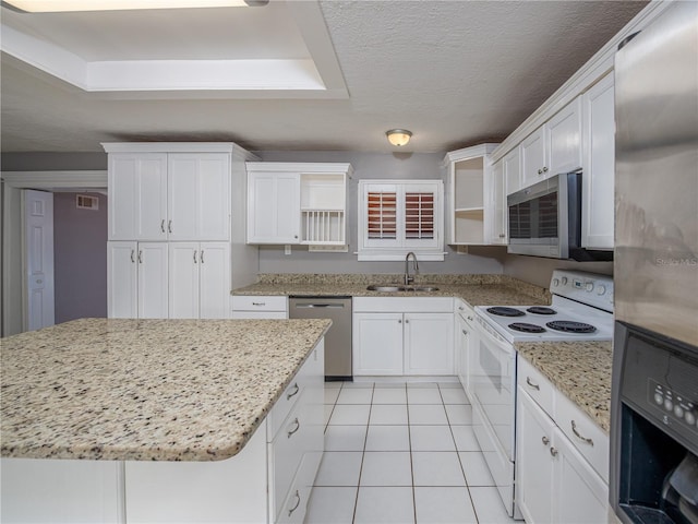 kitchen with light stone countertops, appliances with stainless steel finishes, white cabinets, sink, and light tile patterned flooring