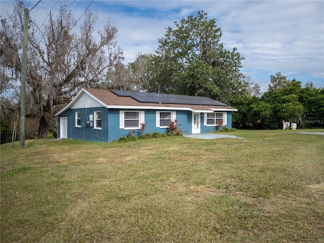 ranch-style home featuring a garage, solar panels, and a front lawn