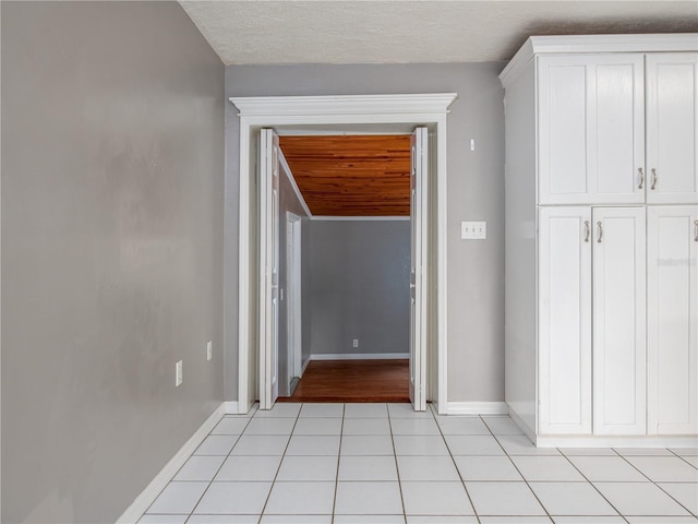 hallway with a textured ceiling and light tile patterned floors