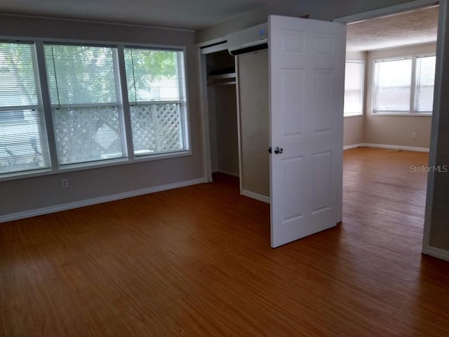 unfurnished bedroom featuring wood-type flooring, a barn door, and a closet