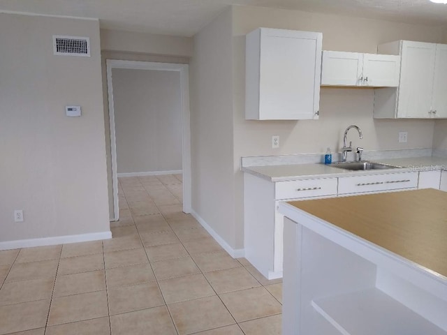 kitchen featuring sink, light tile patterned floors, and white cabinets