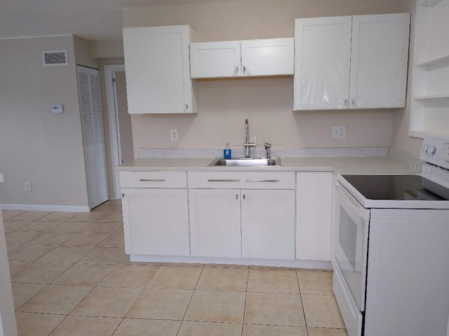 kitchen with light tile patterned flooring, white range with electric cooktop, sink, and white cabinets