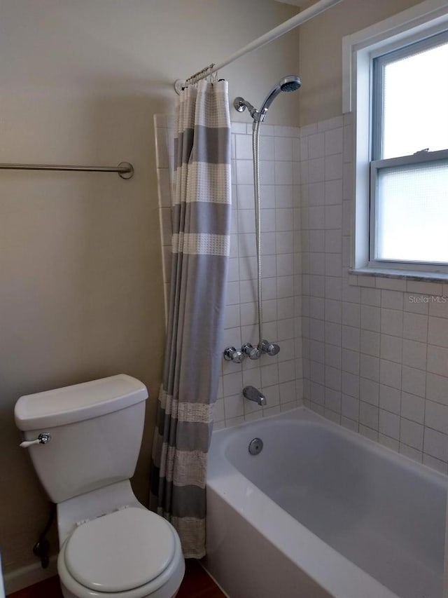 bathroom with shower / bath combination with curtain and toilet