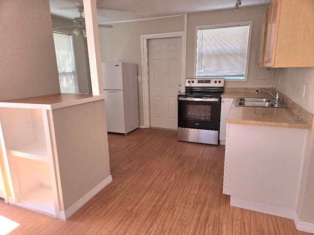 kitchen featuring white refrigerator, light hardwood / wood-style floors, sink, and stainless steel electric range