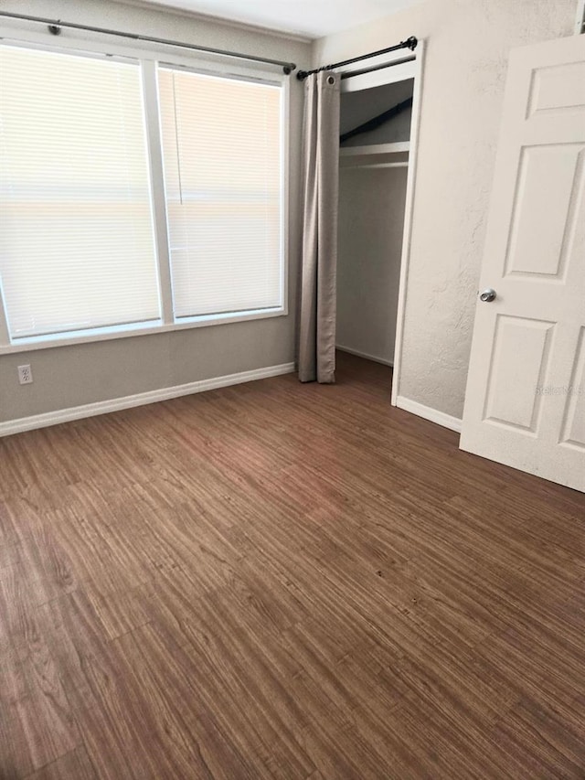 unfurnished bedroom with dark wood-type flooring and a closet