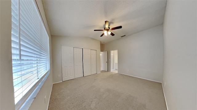 unfurnished bedroom with a textured ceiling, light colored carpet, ceiling fan, a closet, and lofted ceiling