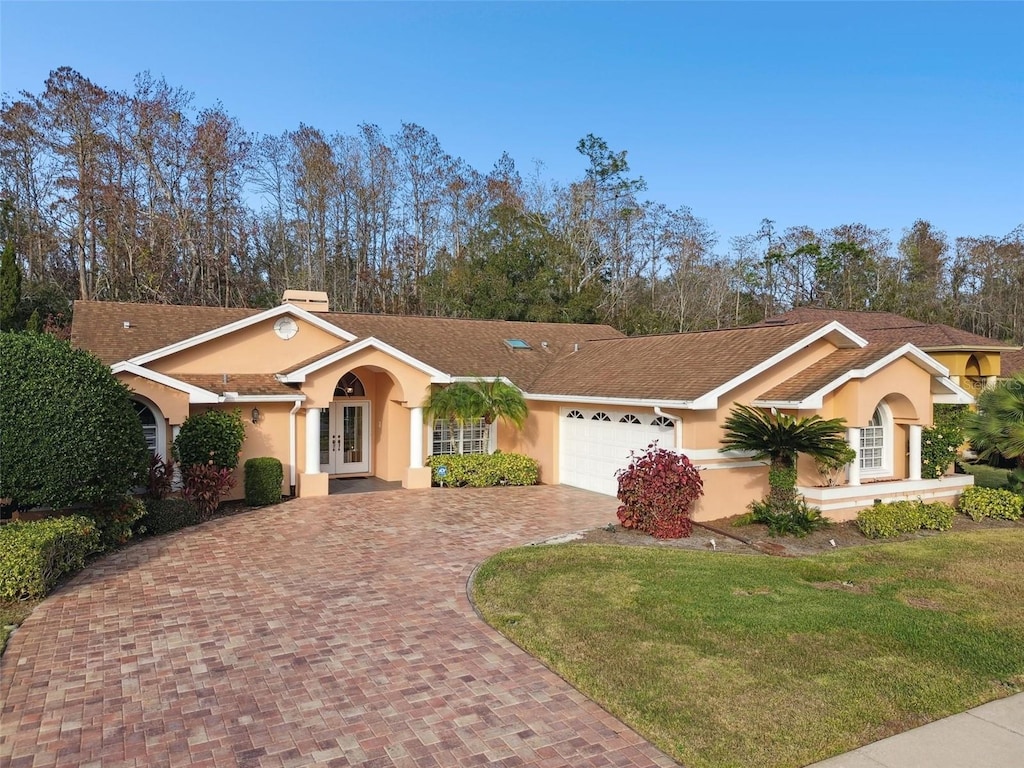 single story home with a garage, a front yard, and french doors