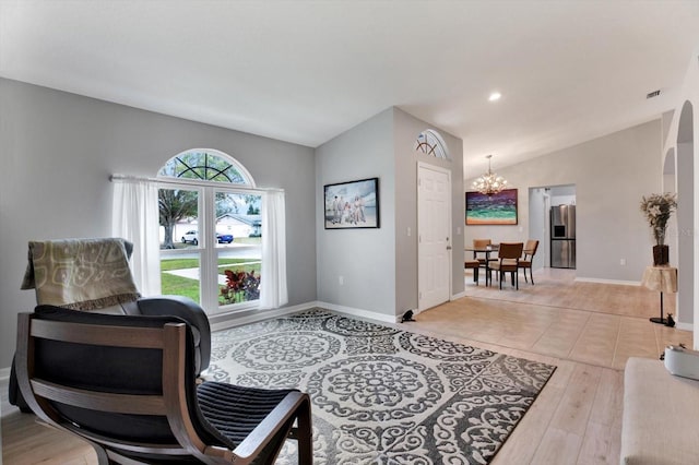 living area featuring light hardwood / wood-style flooring, lofted ceiling, and an inviting chandelier