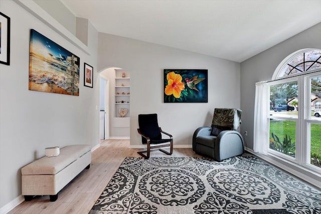 living area with lofted ceiling, light hardwood / wood-style floors, and built in shelves