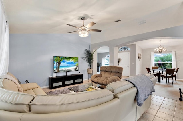 living room featuring ceiling fan with notable chandelier, light tile patterned floors, and vaulted ceiling