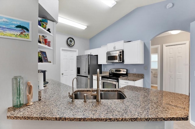 kitchen featuring light stone countertops, appliances with stainless steel finishes, white cabinetry, kitchen peninsula, and vaulted ceiling