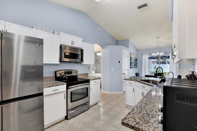 kitchen with white cabinetry, appliances with stainless steel finishes, lofted ceiling, hanging light fixtures, and dark stone counters