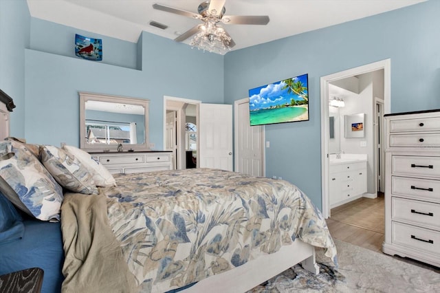 bedroom with ceiling fan, ensuite bath, and light wood-type flooring