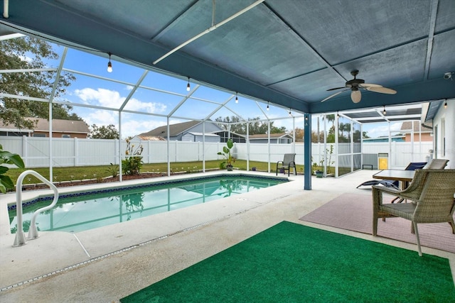 view of swimming pool featuring ceiling fan, glass enclosure, a yard, and a patio