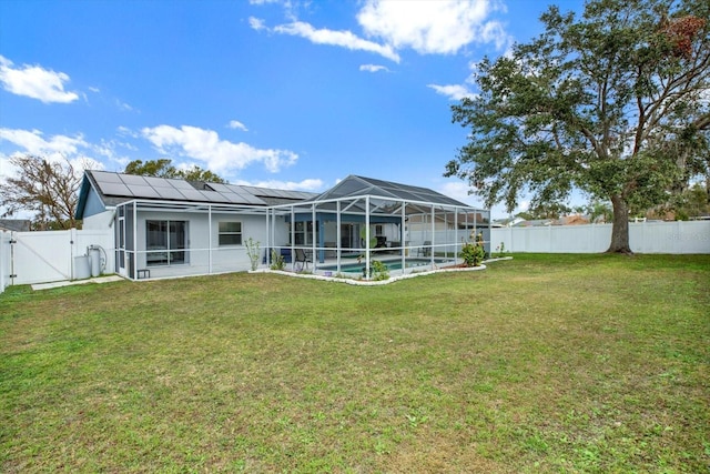 rear view of house with a lanai, a yard, solar panels, and a fenced in pool