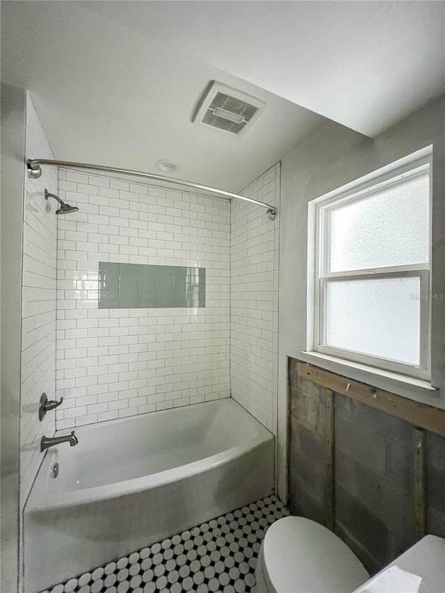 bathroom featuring tile patterned floors, toilet, and tiled shower / bath