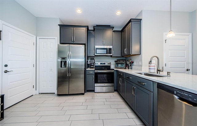 kitchen featuring light stone countertops, pendant lighting, stainless steel appliances, and sink