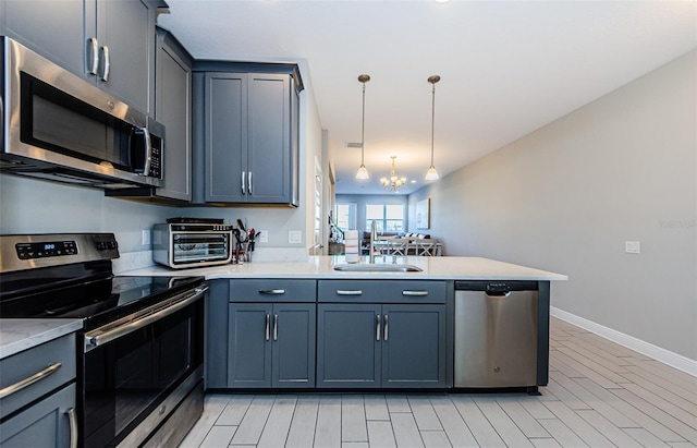 kitchen with sink, hanging light fixtures, stainless steel appliances, an inviting chandelier, and kitchen peninsula