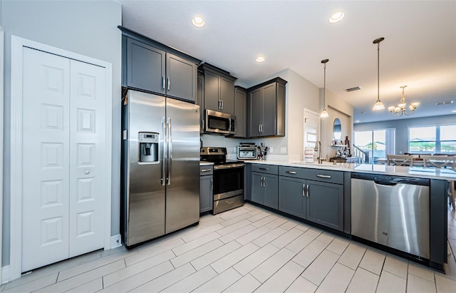 kitchen featuring sink, a chandelier, pendant lighting, gray cabinets, and appliances with stainless steel finishes