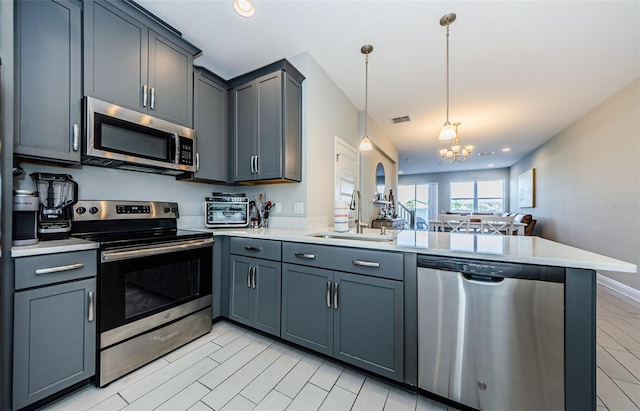 kitchen with sink, decorative light fixtures, appliances with stainless steel finishes, a notable chandelier, and kitchen peninsula