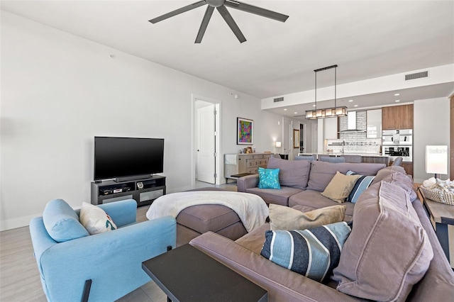 living room with ceiling fan and light hardwood / wood-style flooring