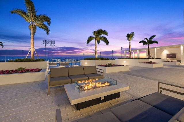 patio terrace at dusk with an outdoor living space with a fire pit