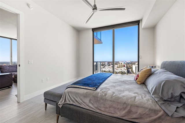 bedroom featuring ceiling fan, multiple windows, a wall of windows, and light hardwood / wood-style flooring