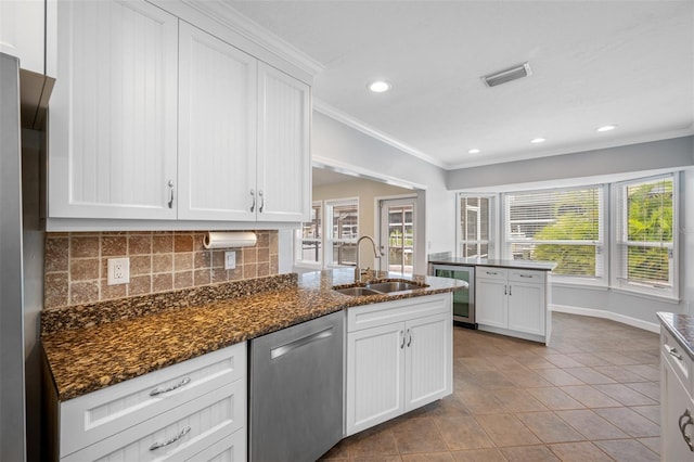 kitchen featuring stainless steel appliances, tasteful backsplash, white cabinetry, dark stone counters, and sink