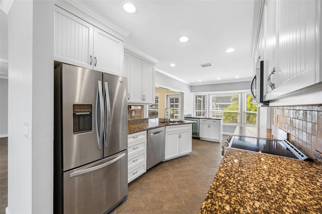 kitchen featuring stainless steel appliances, white cabinets, dark stone countertops, and sink