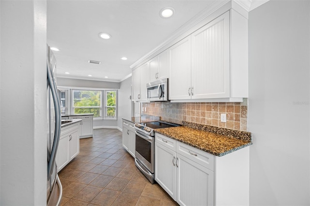 kitchen featuring stainless steel appliances, tasteful backsplash, crown molding, white cabinetry, and dark stone counters